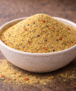 Bol de semoule épicée sur table rustique, parfait pour assaisonnement ou cuisine créative.