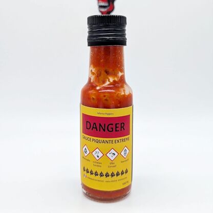 6645598-47f25dd1f9690e.jpg Bouteille de sauce piquante extrême avec étiquettes de danger et avertissements. Usage réservé aux amateurs de piments forts.