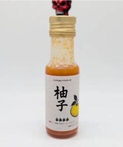 Petite bouteille de sauce au yuzu avec étiquette japonaise, bouchon doré et image d'un citron.