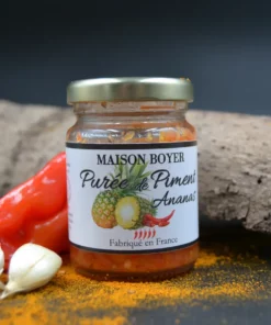 Purée de piment ananas Maison Boyer, fabriquée en France, pot épicé avec ingrédients frais en arrière-plan.