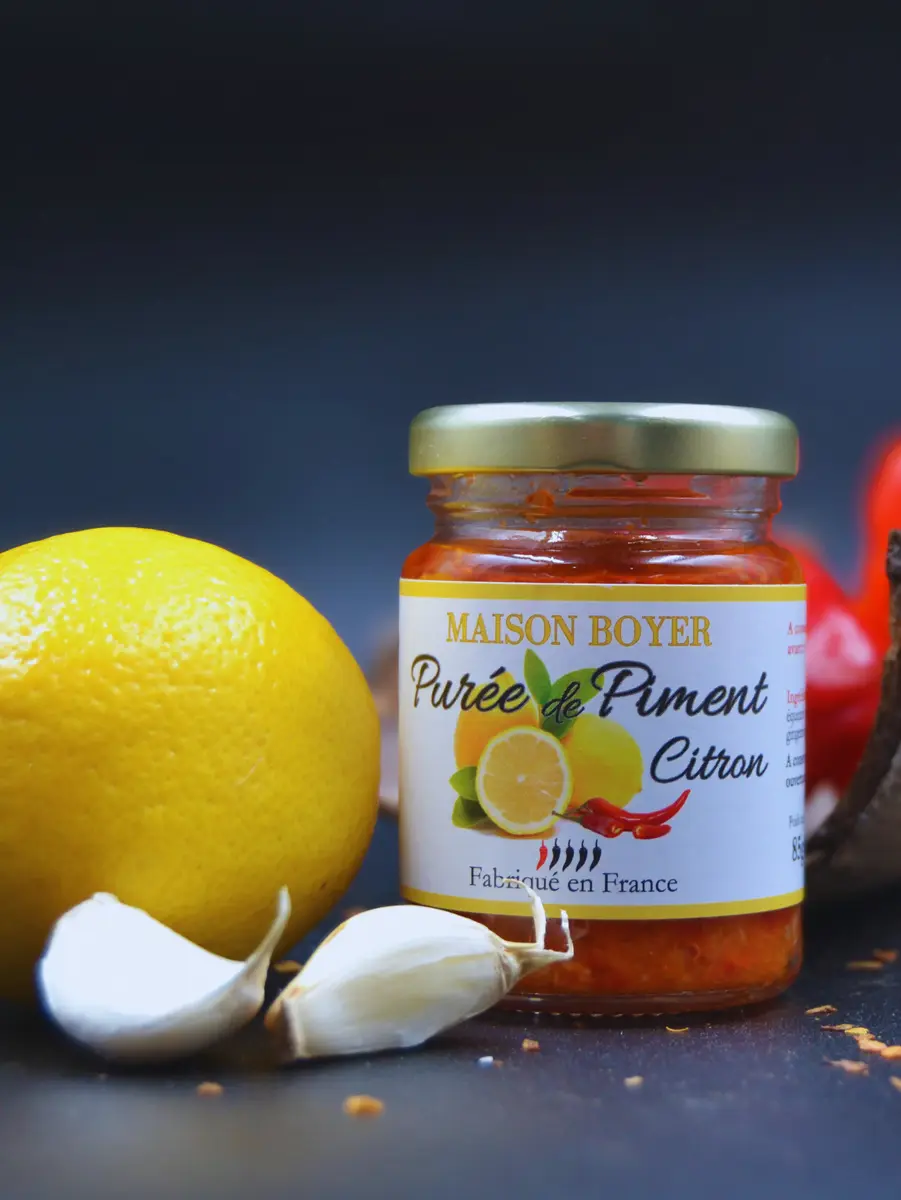 puree-piment-citron-legere-force-1.webp Pot de purée de piment citron Maison Boyer avec citron et ail, fabriqué en France, fond noir.