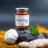 Bocal de purée de piment rouge Maison Boyer avec ail, gingembre et persil, fond coloré aux épices.