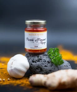 Bocal de purée de piment rouge Maison Boyer avec ail, gingembre et persil, fond coloré aux épices.