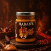 Pot de sauce piquante Haban's entouré de piments, idéale pour relever vos plats avec saveur et intensité.